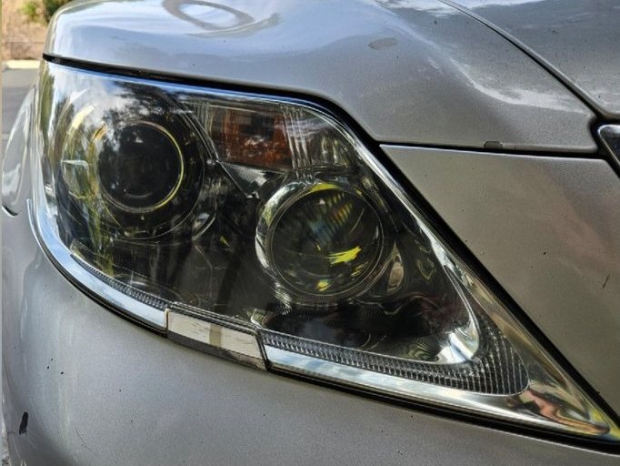 The same Lexus sedan headlight after restoration, clear enough to see the reflector