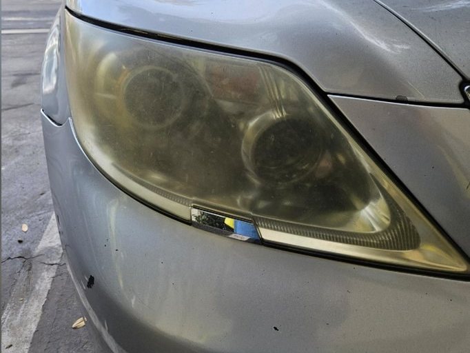 Lexus sedan headlight before restoration, yellowed and hazed over